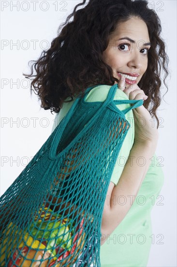 Mixed race woman holding reusable grocery bag