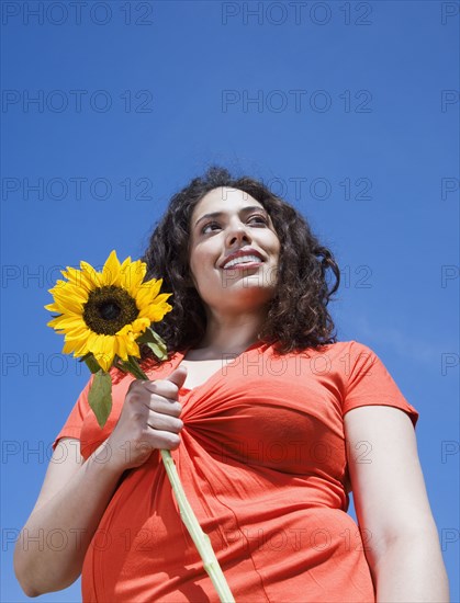 Mixed race woman holding sunflower outdoors