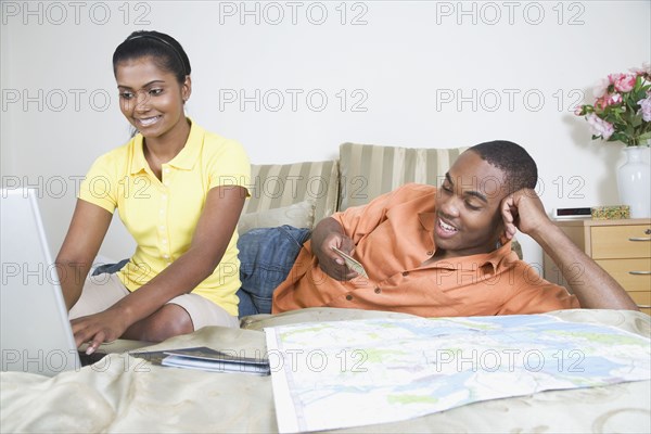 Multi-ethnic couple looking at map and laptop