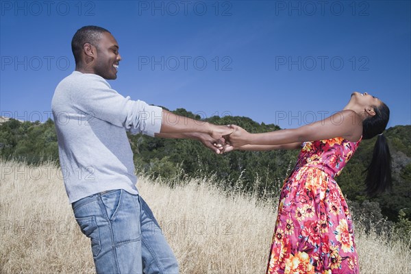 Multi-ethnic couple holding hands in rural area