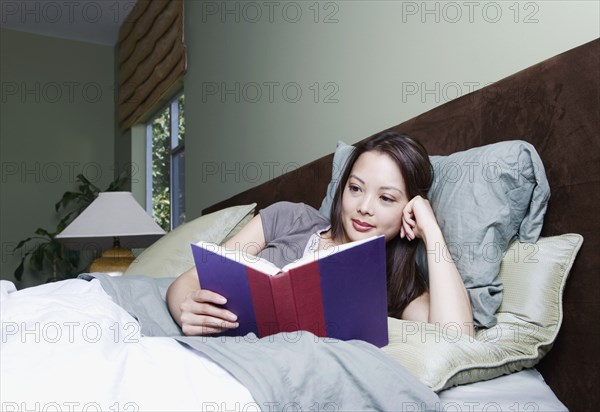 Woman reading book in bed