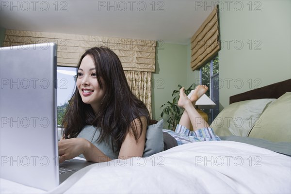 Woman using laptop in bed