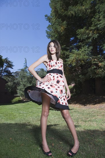 Mixed race girl twirling dress in park