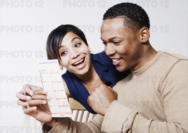 Excited couple looking at lottery ticket