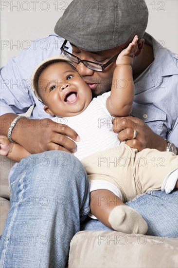 African American holding and kissing baby son in lap