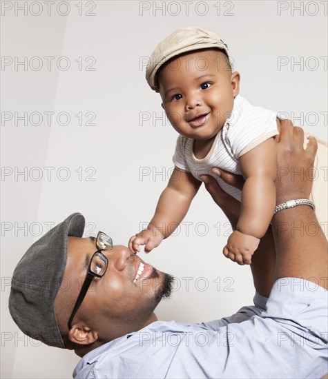 African American man lifting baby son into the air