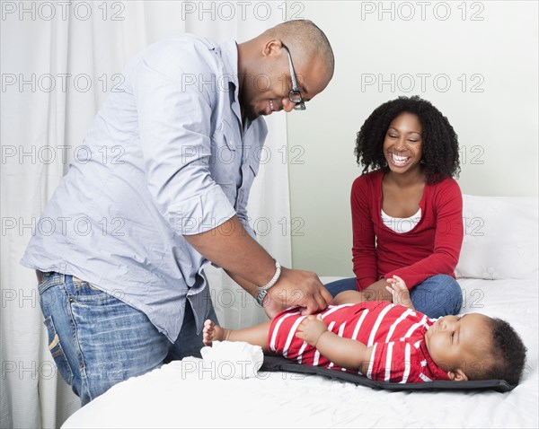 African American father changing baby son's diapers