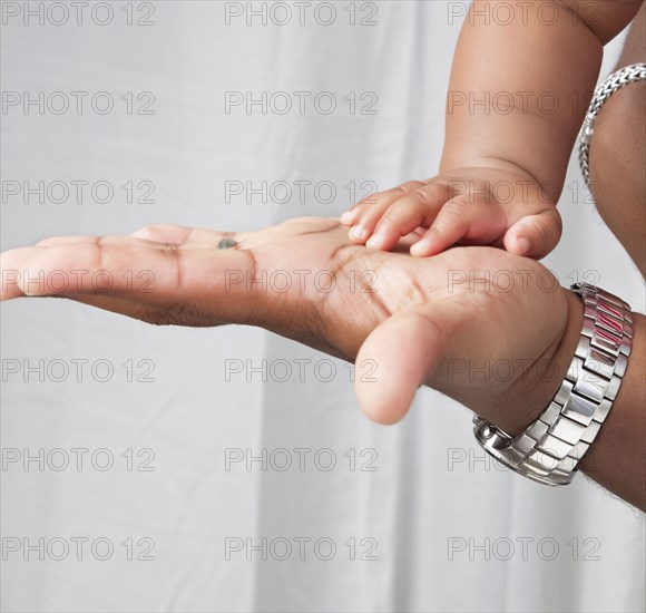 Close up of African American father and baby son's hands