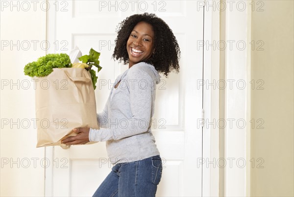 African American woman carrying bag of groceries