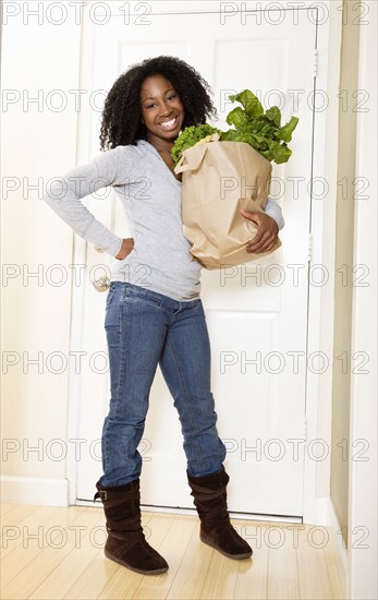 African American woman carrying bag of groceries