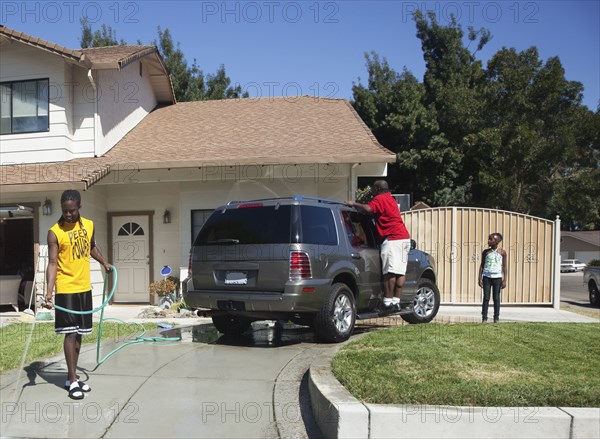 Black family washing car in driveway