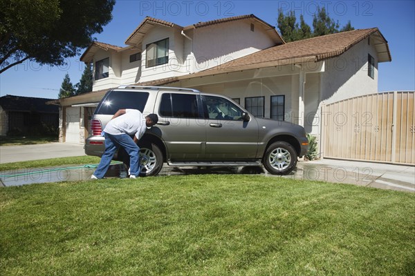 Black man washing car in driveway