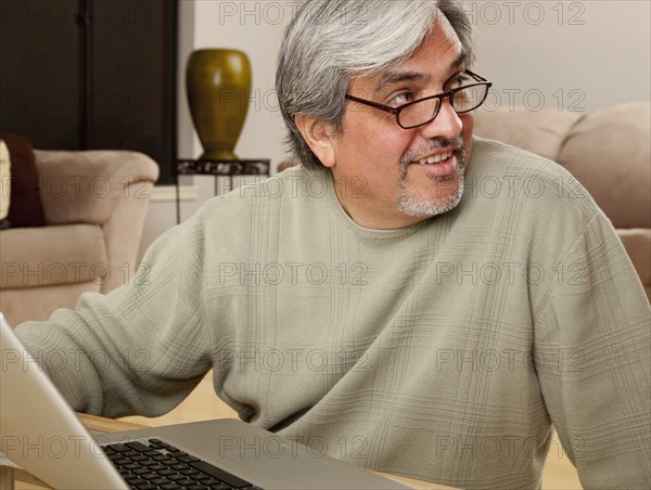 Hispanic man using laptop in living room