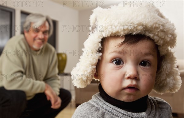 Grandfather watching granddaughter in winter cap