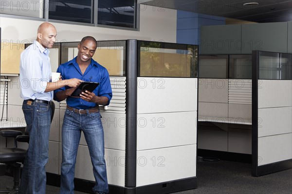 Mixed race businessmen using digital tablet in office