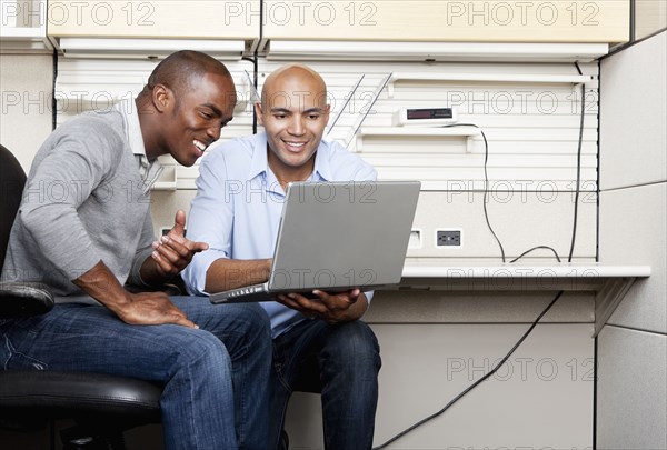 Mixed race businessmen working together in office cubicle