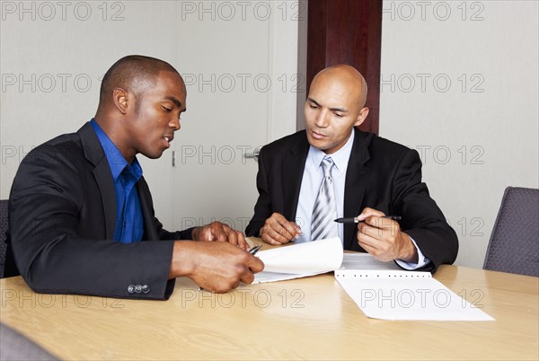 Mixed race businessmen reviewing contract in conference room