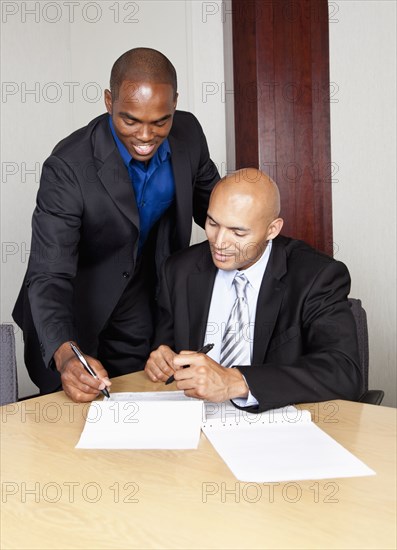 Mixed race businessmen reviewing contract in conference room