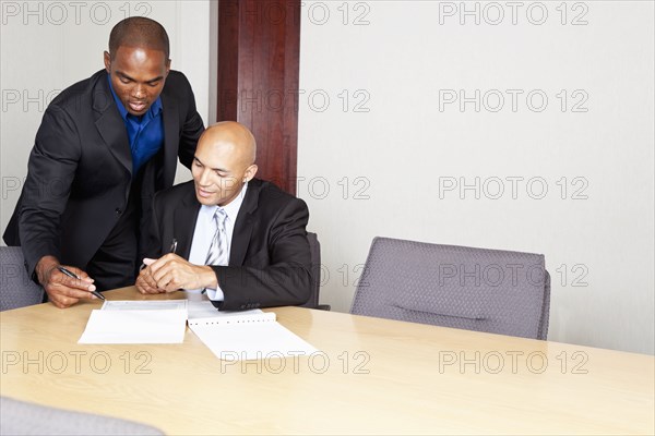 Mixed race businessmen reviewing contract in conference room