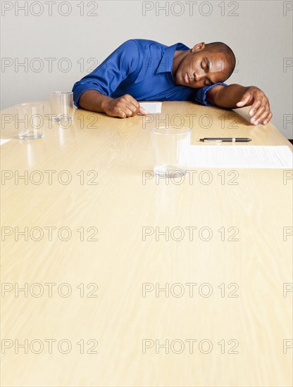 Mixed race businessman sleeping on conference room table