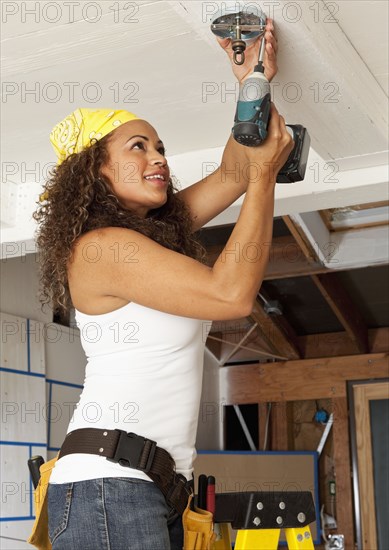 Hispanic woman using cordless drill