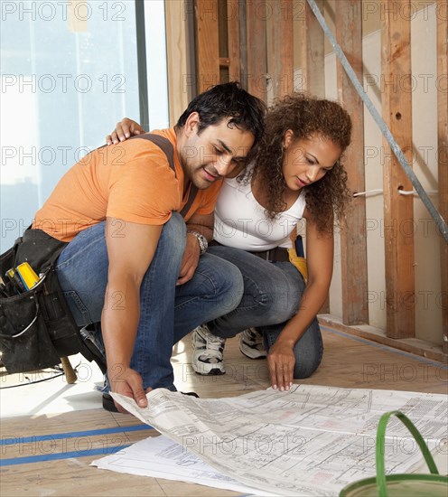 Hispanic couple looking at blueprints