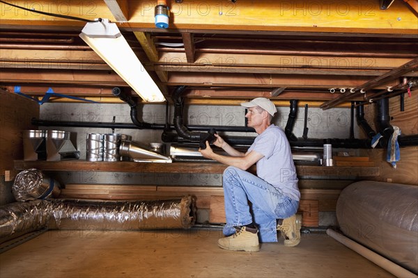 Caucasian plumber working on pipes