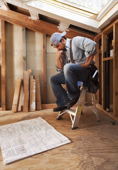 Hispanic construction worker looking at blueprints