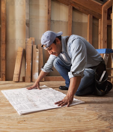 Hispanic construction worker looking at blueprints