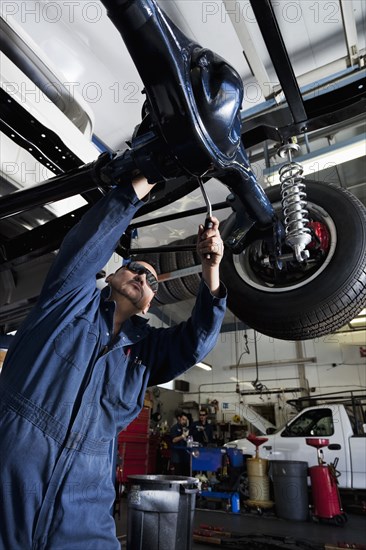 Hispanic mechanic working on car