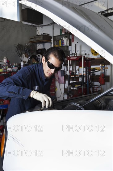 Hispanic mechanic working on car
