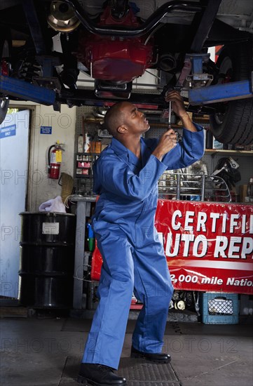 Black mechanic working on car