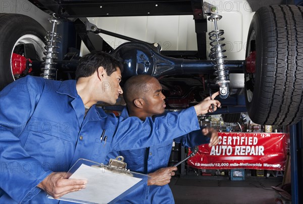 Mechanics working on car shock absorbers