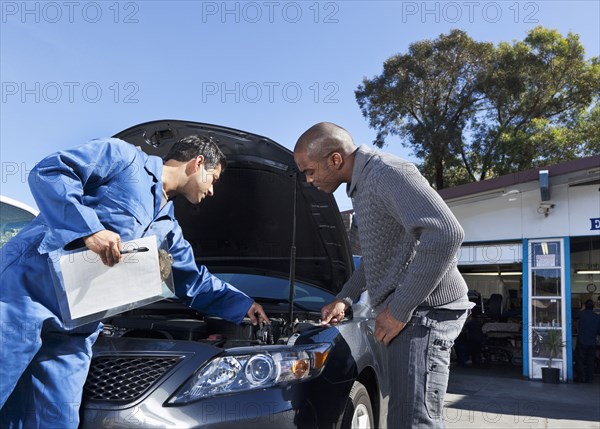 Mechanic talking to customer about car engine