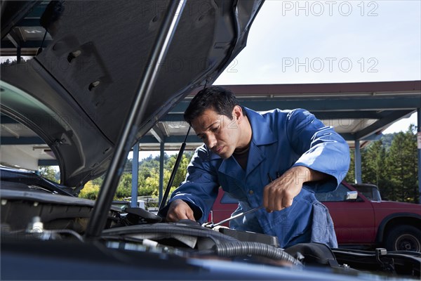 Middle Eastern mechanic working on car engine