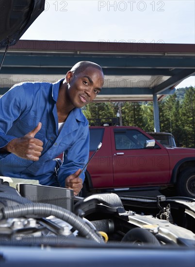 Black mechanic working on car engine