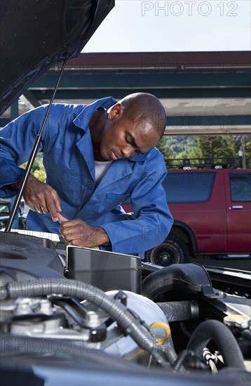 Black mechanic working on car engine