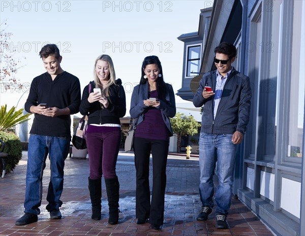 Friends using cell phones outdoors