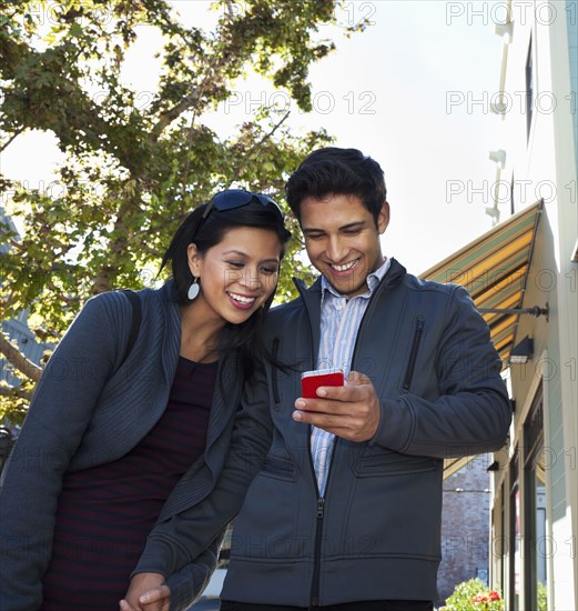 Mixed race couple using cell phone outdoors