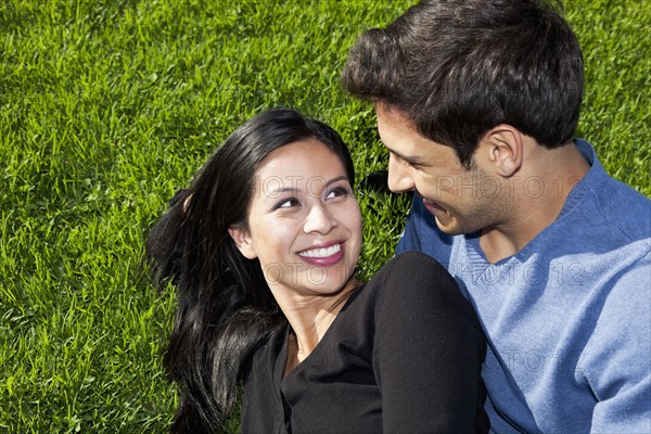 Mixed race couple relaxing together in grass