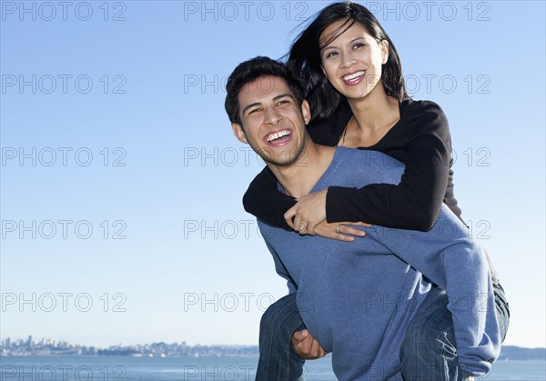 Mixed race man carrying girlfriend piggy back