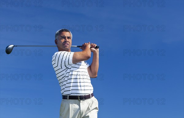 Mixed race man playing golf outdoors