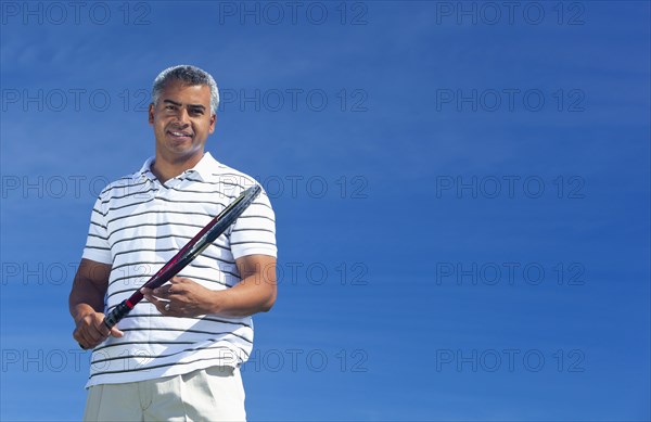 Mixed race man playing tennis outdoors