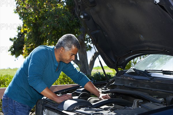 Mixed race man working on car engine