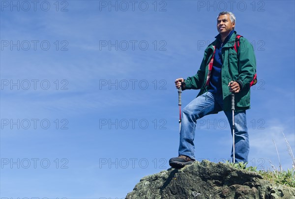 Mixed race man hiking on rocky hill
