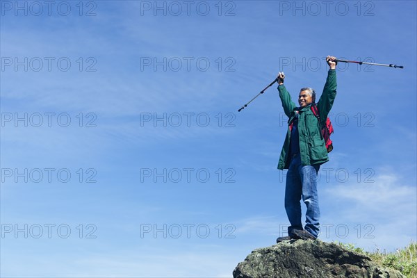 Mixed race man hiking on rocky hill