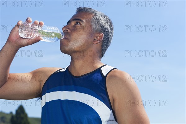 Mixed race man drinking water bottle