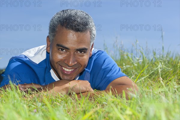 Mixed race man laying in grass