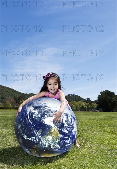 Mixed race girl playing with globe in park