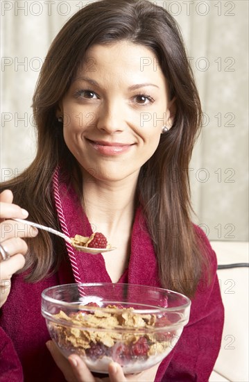 Mixed race woman eating cereal on sofa